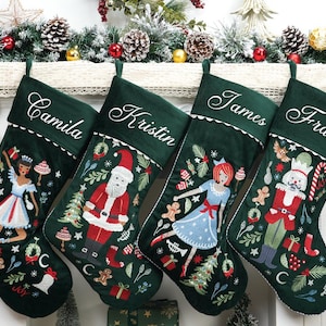 May include: Four dark green velvet Christmas stockings featuring white embroidered names Camila, Kristin, James, and Frank. Each stocking displays colourful holiday-themed embroidery including a ballerina, Santa Claus, and a nutcracker surrounded by festive motifs.
