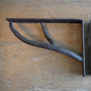 May include: Two black metal shelf brackets with a branch-like design. The brackets are made of wrought iron and have a rustic look.