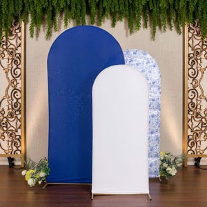 May include: Three arch-shaped fabric backdrops in a wedding or event setting. The backdrops are in blue, white, and a blue floral pattern. The white backdrop is in the center, with the blue backdrop to the left and the floral pattern to the right. The backdrops are on gold metal stands.