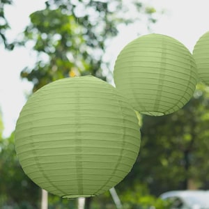 May include: Three round, light green paper lanterns hanging outdoors. The lanterns are made of pleated paper and are suspended by thin wires. The background is blurred, showing green foliage.