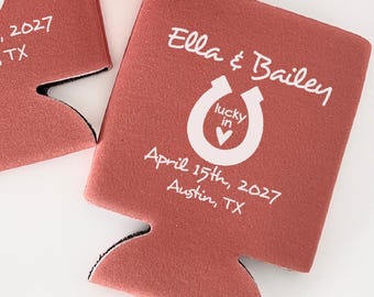 May include: Two rust-colored foam can coolers and one can cooler sleeve holding a silver beverage can. Each features white text reading Ella & Bailey, a horseshoe icon with a heart, and the date April 15th, 2027, in Austin, TX.
