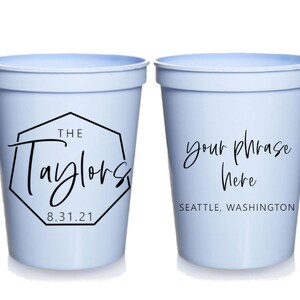 May include: Two light blue plastic cups with black text. The first cup says "The Taylors 8.31.21" inside a black octagon. The second cup says "your phrase here" and "SEATTLE, WASHINGTON".