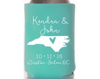 May include: A teal foam can cooler featuring the white printed text Kendra & John, a white silhouette of North Carolina with a heart, the date 10.11.16, and the location Winston-Salem, NC. The sleeve is wrapped around a silver metal beverage can.