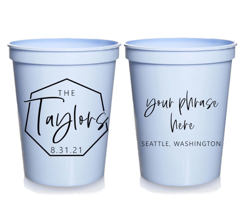 May include: Two light blue plastic cups with black text. The first cup says "The Taylors 8.31.21" inside a black octagon. The second cup says "your phrase here" and "SEATTLE, WASHINGTON".
