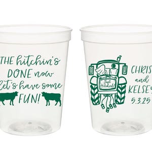 May include: Two clear plastic cups with green text and graphics. The left cup says "THE hitchin's DONE now let's have some FUN!" with two cows on either side of the text. The right cup has a drawing of a tractor with a bride and groom in the back. The text on the right cup says "CHRIS and KELSEY 5.3.25".