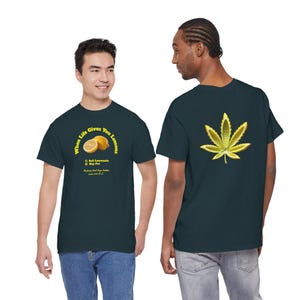 Könnte beinhalten: Zwei dunkelblaue T-Shirts. Eines zeigt den Text "When Life Gives You Lemons" mit einer Zitronengrafik und dem Text "1) Sell Lemonade 2) Buy Pot". Das andere Shirt hat eine gelb-grüne Cannabisblatt-Grafik.