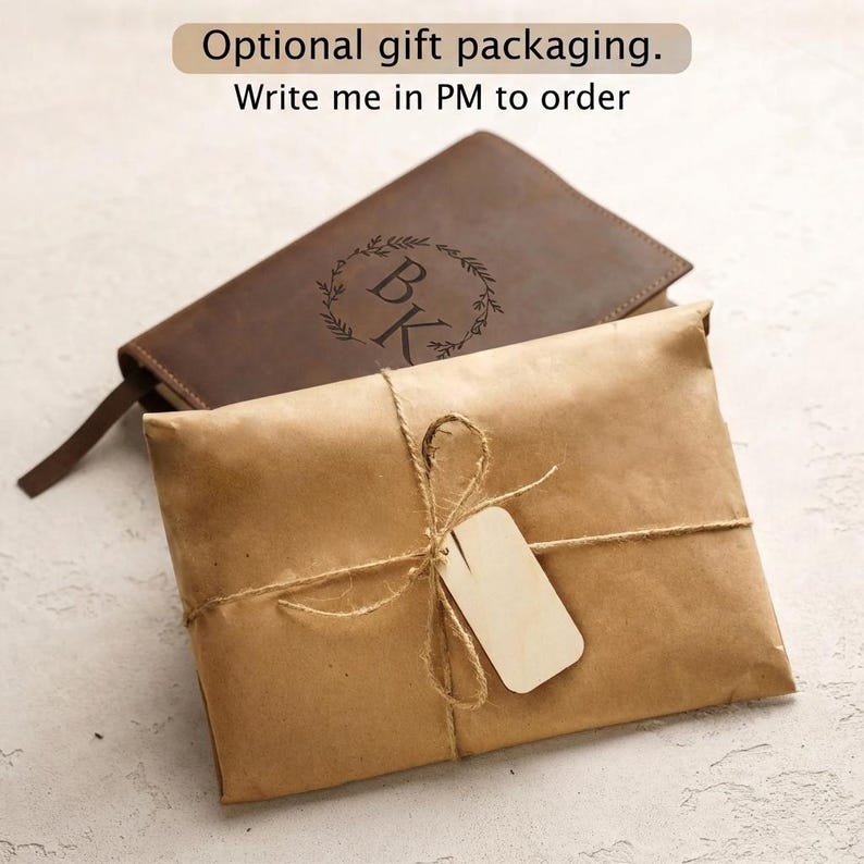 May include: A dark brown leather journal with a circular wreath engraving and the letters BK, accompanied by a brown paper gift package tied with twine and a blank rectangular wooden tag. Text reads: Optional gift packaging. Write me in PM to order.