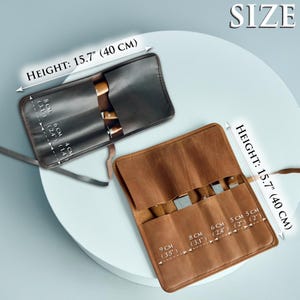 May include: Two leather knife rolls, one black and one brown, are displayed. Each roll is open, revealing the slots for knives. The height of each roll is 15.7 inches (40 cm). The text "SIZE" is visible.
