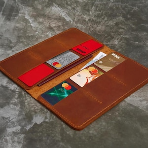 May include: Open, brown leather wallet with multiple card slots. The wallet is filled with various credit cards, including Visa and Mastercard. The interior is lined with a darker brown material. The wallet is open, displaying its contents.