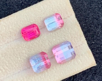 May include: Four rectangular gemstones with a gradient of colors. One is a solid magenta, while the others transition from pink to light blue. They are displayed on a beige, textured surface against a dark background.