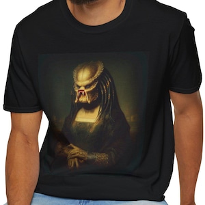 May include: Black t-shirt featuring a parody of the Mona Lisa, with the Predator's mask replacing the woman's face. The artwork is in a classic portrait style, with a gold and red mask. The shirt is made of a soft material.