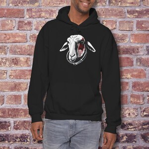 May include: Black hooded sweatshirt featuring a white sheep graphic with red accents on the face. The sheep has a collar with text. The sweatshirt is made of a soft material and has long sleeves. The model is wearing blue jeans.