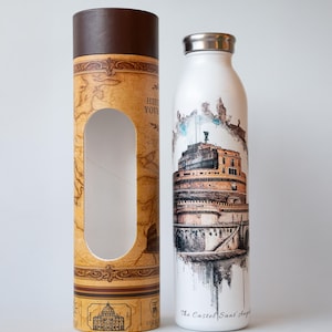 Op de afbeelding: Witte waterfles met een zilveren dop, met een aquarel illustratie van de Engelenburcht in Rome. De fles staat naast een cilindrische kartonnen doos met een kaartontwerp en een bruine bovenkant.