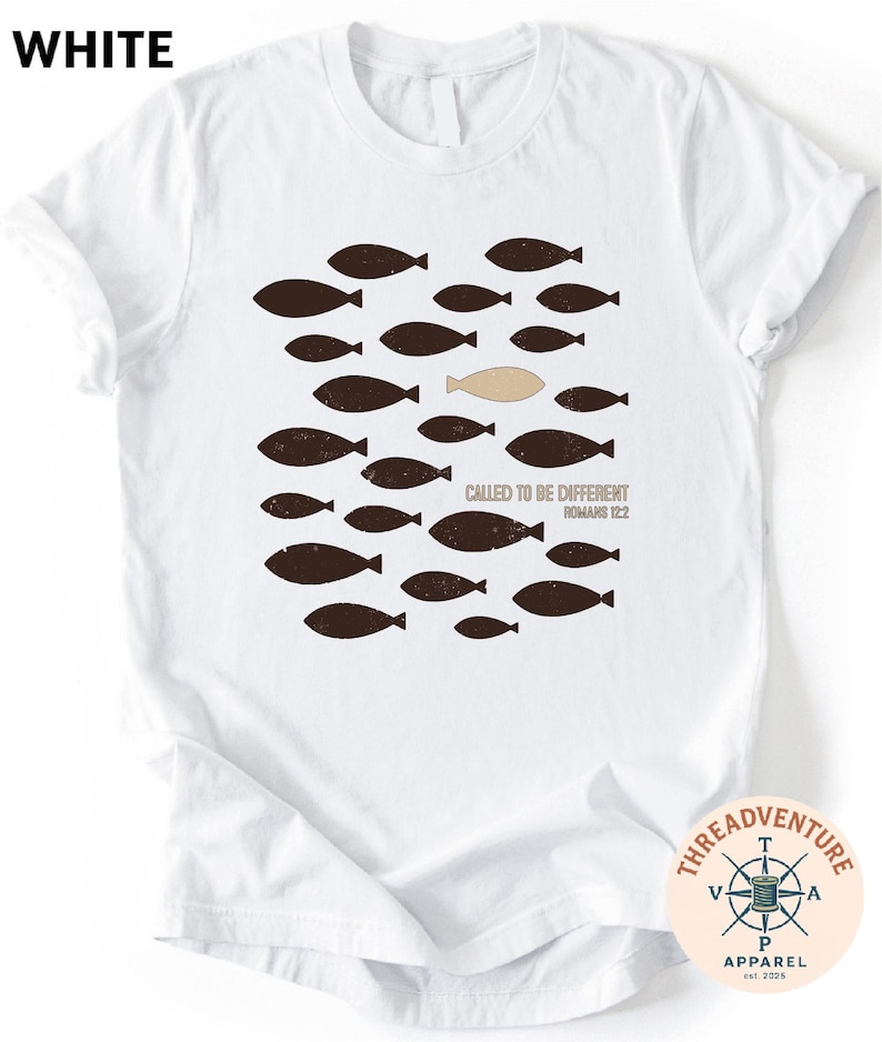 A white t-shirt with a graphic design featuring a group of fish and a single fish in a unique position, along with the text "Called to be Different Romano 122".