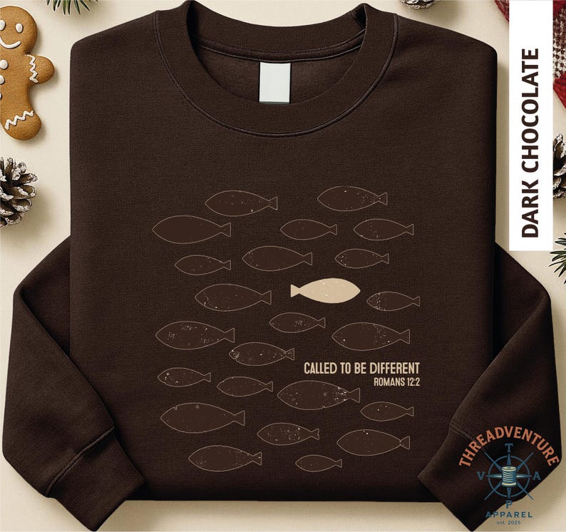 A brown long-sleeved t-shirt with a graphic design of fish and a single fish in the center, along with text that reads "CALLED TO BE DIFFERENT ROMANS 12:2".