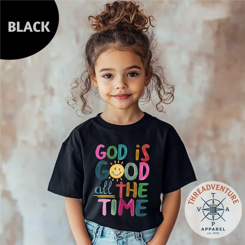 May include: A black t-shirt with the text "GOD IS GOOD all THE TIME" in colorful, playful lettering. The design includes a smiling sun graphic. The shirt is from Threadventure Apparel, est. 2025.