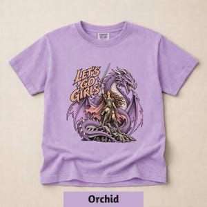 A purple t-shirt with a graphic design depicting a woman with long hair and a dragon on a rock.