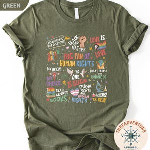 The image is a t-shirt with a graphic design featuring various phrases and symbols related to LGBTQ+ rights and diversity.