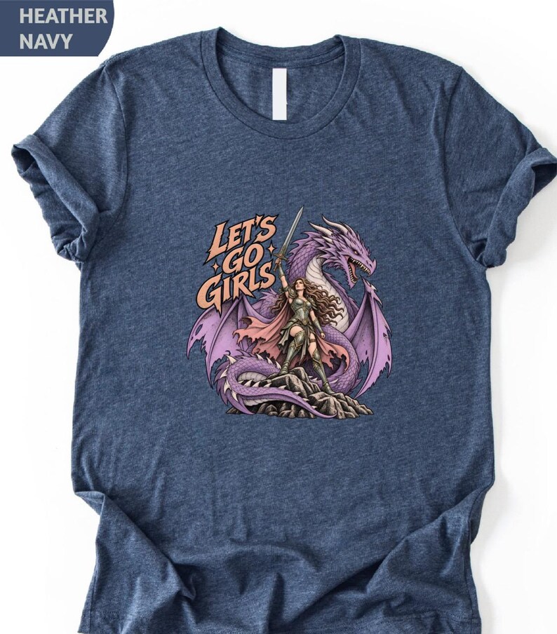 A navy blue t-shirt with a graphic design depicting a woman standing on a rock with a purple dragon behind her. The text on the t-shirt reads "Let's go girls".