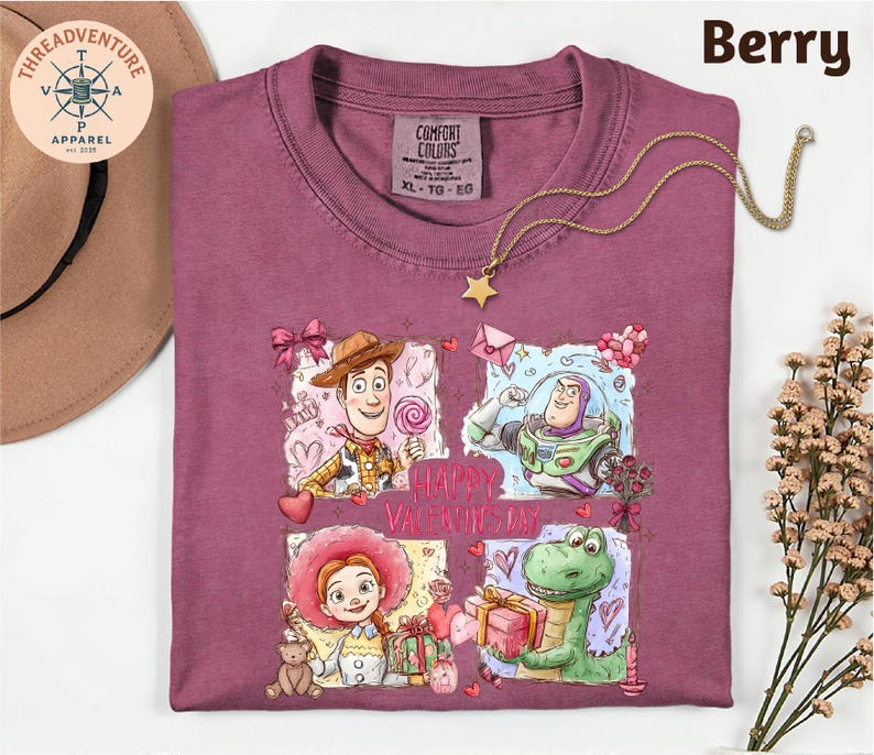 a purple t-shirt with a graphic design of characters from the Toy Story movie, including Woody, Buzz Lightyear, and an anthropomorphic dinosaur. The design also includes a "Happy Valentine's Day" message. The t-shirt is displayed on a white background, along with a hat, a necklace, and some flowers.
