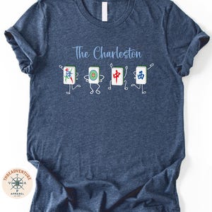 A blue t-shirt with a graphic design featuring four cartoon-like characters and the text "The Charleston" printed on it.
