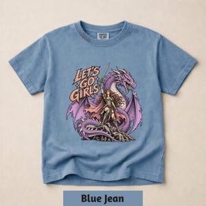 A blue t-shirt with a graphic design depicting a woman with a sword and a purple dragon.