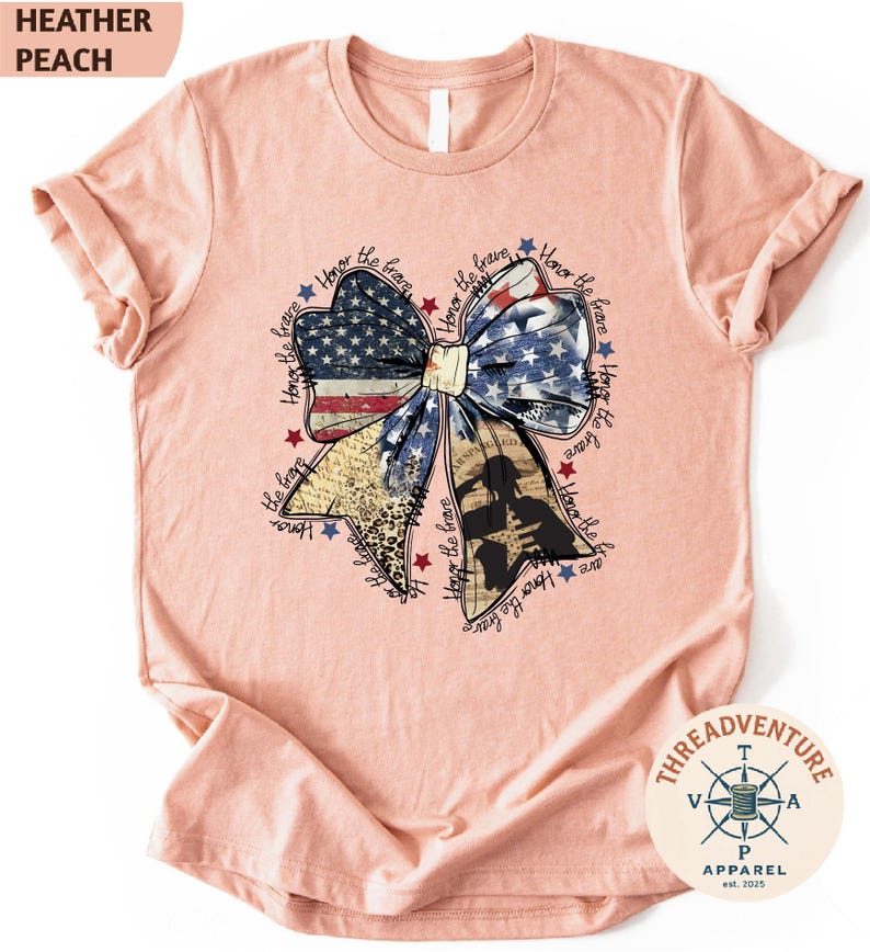 A pink t-shirt with a patriotic design featuring a large bow made up of American flag colors and stars.