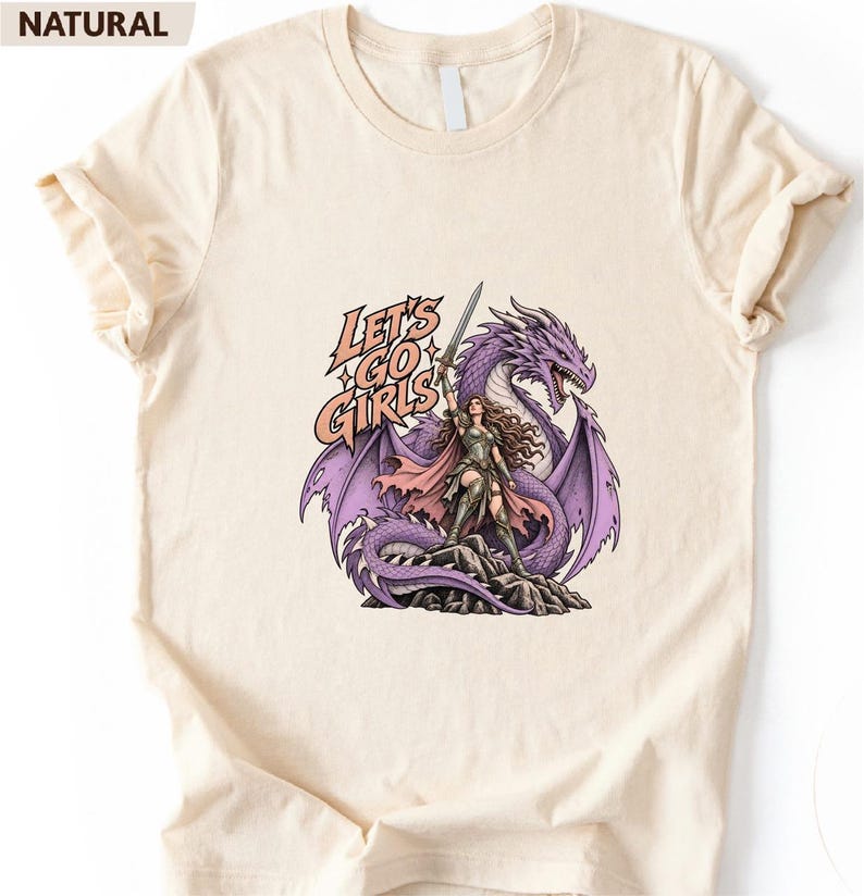 A white t-shirt with a graphic design depicting a woman standing next to a purple dragon. The text on the t-shirt reads "Let's go girls".