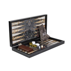 May include: Open backgammon set with a black frame and a marble-like playing surface. Includes brown leather case, dice, and game pieces. A drawstring bag with the text "RCH MM" is also included.