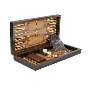 Könnte beinhalten: Offenes Backgammon-Set mit dunklem Holz außen und gemustertem Innenraum. Das Set enthält braune und weiße Spielsteine, Würfel und einen braunen Kordelzugbeutel. Der Innenraum weist ein dekoratives Design auf.