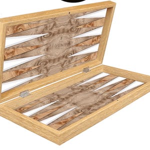 May include: An open wooden backgammon board featuring a light oak frame and a burl wood playing surface with white and brown triangular points. The interior lid displays the text THE STAUNTON CHESS COMPANY in a centered, engraved font.