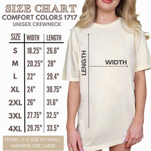 May include: Cream-colored unisex crewneck t-shirt with a size chart. The chart displays measurements in inches for sizes S to 4XL. The text on the chart reads "COMFORT COLORS 1717" and "UNISEX CREWNECK". The model is wearing a size large.