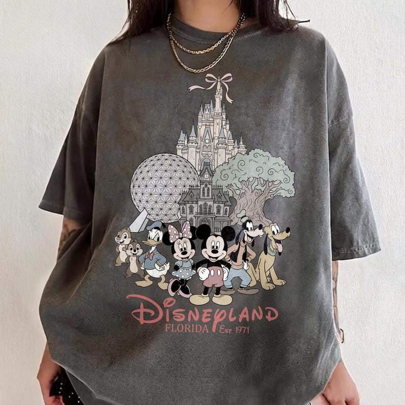K&ouml;nnte beinhalten: Dunkelgraues T-Shirt mit einem Disney-Motiv. Das Design zeigt Micky und Minnie Maus, ein Schloss und Spaceship Earth. Der Text "Disneyland Florida Est. 1971" ist darunter gedruckt.