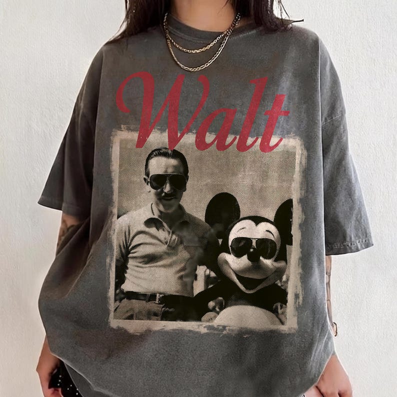 May include: Grey t-shirt with a vintage image of Walt Disney and Mickey Mouse wearing sunglasses. The word "Walt" is printed in red above the image. The shirt has short sleeves and a relaxed fit.