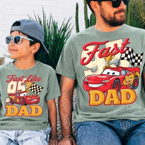 May include: Two matching green t-shirts with a red race car graphic, the text "Fast like 95" and "DAD". One shirt is worn by a child wearing a blue cap and sunglasses. The other shirt is worn by an adult.