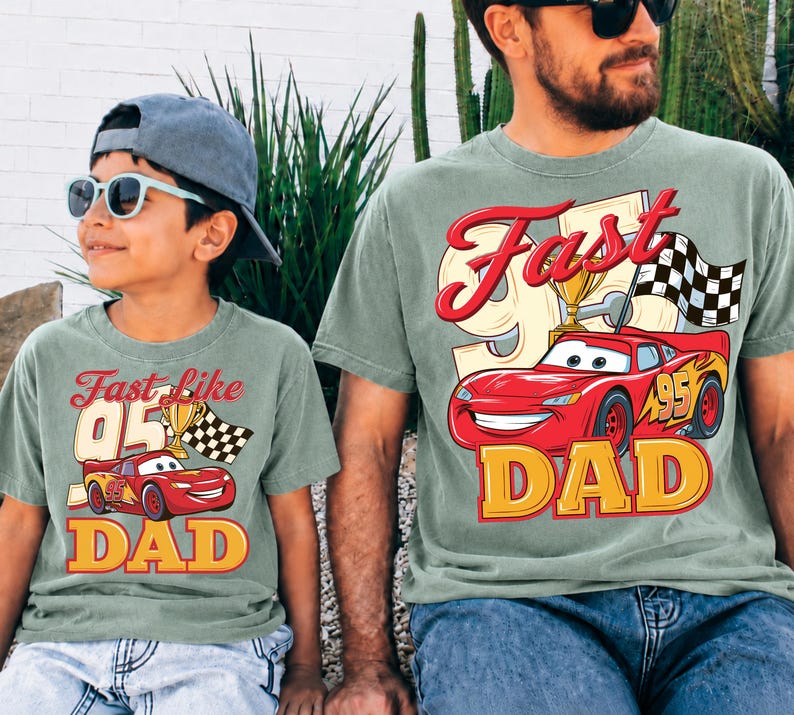 May include: Two matching green t-shirts with a red race car graphic, the text "Fast like 95" and "DAD". One shirt is worn by a child wearing a blue cap and sunglasses. The other shirt is worn by an adult.