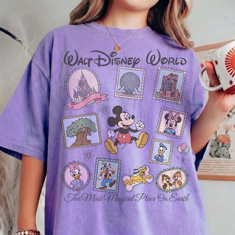 May include: A lavender t-shirt featuring a Walt Disney World design. The shirt showcases various Disney characters and park icons within postage stamp-like frames. Text includes "Walt Disney World" and "The Most Magical Place On Earth."