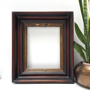 May include: A rectangular wooden picture frame featuring a deep mahogany finish with a dark brown outer edge and a contrasting inner border in a muted gold tone. The frame has a stepped, multi-layered profile with visible wood grain textures.
