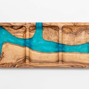 Könnte beinhalten: Ein rechteckiges Serviertablett aus Holz mit drei Fächern und einem türkisfarbenen Harzfluss-Design. Das Tablett besteht aus hellbraunem Holz mit dunkelbraunen Maserungsmustern.