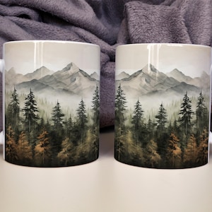 May include: Two white ceramic mugs featuring a wrap-around watercolor illustration of a dense forest with tall pine trees in shades of green and brown, set against a backdrop of misty, layered mountain peaks in soft gray and white tones.