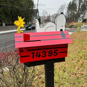 May include: Red mailbox with black stripes and the number 14395. A white dog and a yellow bird are on top of the mailbox.