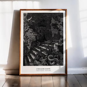 Peut inclure: Œuvre d'art encadrée en noir et blanc représentant une scène hantée avec un escalier, des créatures et des éléments architecturaux. L'œuvre est dans un cadre en bois et est appuyée contre un mur blanc. Le texte "L'ESCALIER HANTÉ" est visible en bas.