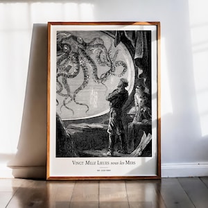 Peut inclure: Illustration en noir et blanc encadrée représentant un calmar géant attaquant un navire, avec deux personnages observant. L'œuvre est intitulée "Vingt Mille Lieues sous les Mers" par Jules Verne. Le cadre est de couleur marron chaud.
