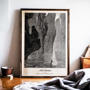 May include: Framed black and white print depicting a person in water, with a large rock formation on the left and a light beam on the right. The text "le Mer Centrale" is at the bottom.