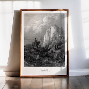 May include: Black and white framed print of a detailed illustration depicting the city of Camelot. The artwork features a medieval castle on a cliff, figures on horseback, and the word "Camelot" at the bottom. The frame is a warm brown color.