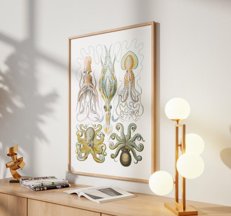 May include: A framed vintage-style print featuring detailed illustrations of various cephalopods, including octopuses and squid, in shades of yellow, blue, and green. The artwork is displayed on a light-colored wall, with a wooden frame.