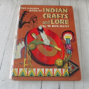 May include: The Golden Book of Indian Crafts and Lore by W. Ben Hunt. The cover features a colorful illustration of Native American crafts and symbols, including a headdress, a shield, and a beaded design.