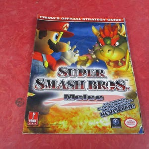 May include: A Prima Games strategy guide for Super Smash Bros. Melee. The cover features Mario and Bowser in a battle scene with the game's title. The guide promises to reveal all trophies, stages, characters, and play modes.