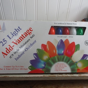 May include: A rectangular box for a 25 light Add-Vantage C9 style miniature indoor-outdoor light set. The packaging features colorful bulb illustrations, text stating an overall length of 26 feet, and notes on energy efficiency and connectivity.