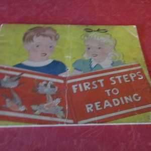 以下が含まれることがあります： 「First Steps to Reading」というタイトルのヴィンテージ子供向け本の表紙。表紙には、2人の子供と鳥やカメのイラストが描かれています。背景は黄色です。